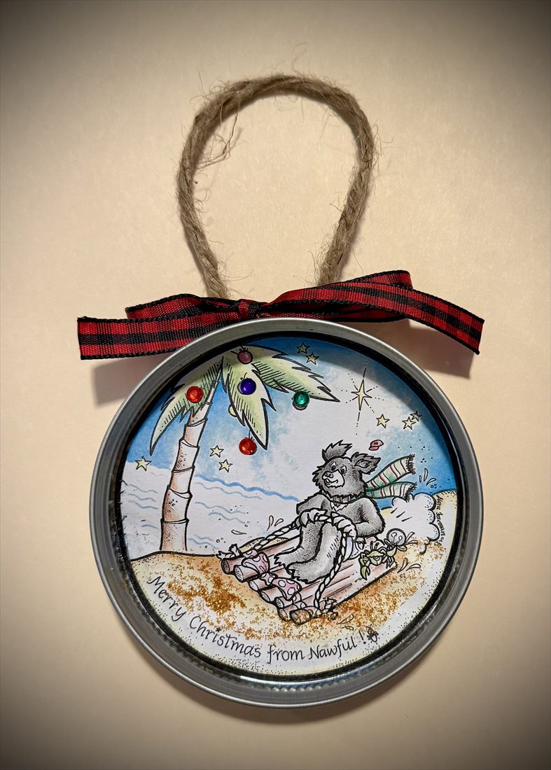 A finished ornament in a mason jar lid with a twine hanger and red plaid bow