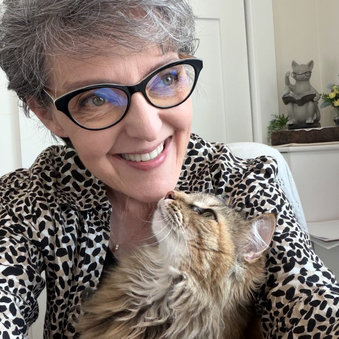 Alora smiling with Ginger, her fluffy long-haired cat, nuzzling her chin