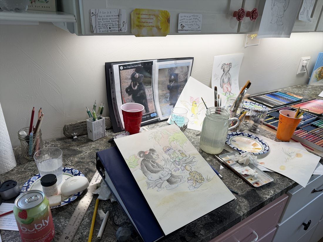 A painting in progress surrounded by colored pencils, brushes, and printed photos of sloth bears