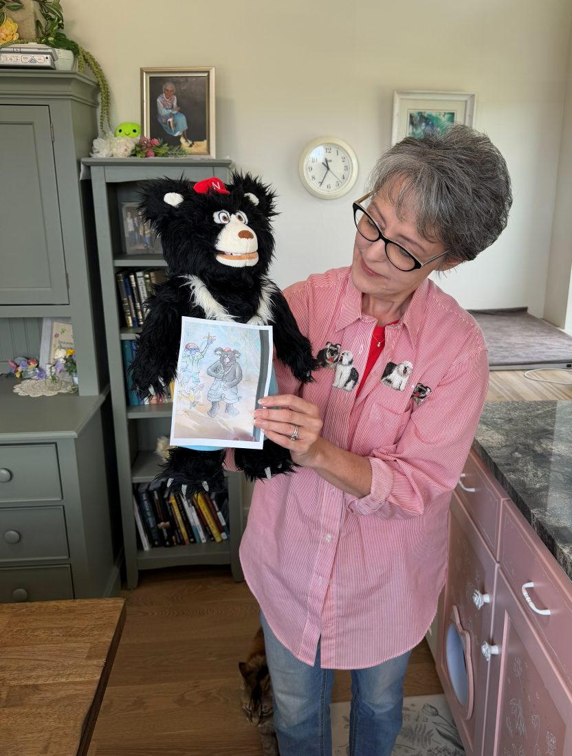 Alora holding the Nawful puppet as he holds up a picture of himself